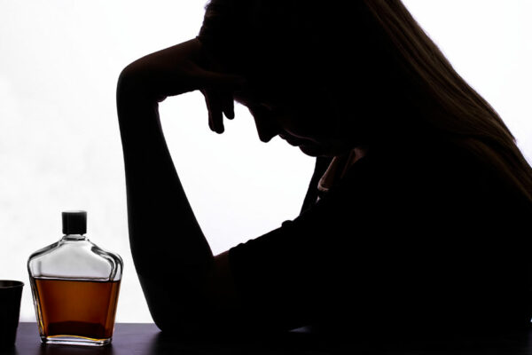 Woman With Alcohol And Shot Glass Holding Her Head In Hands