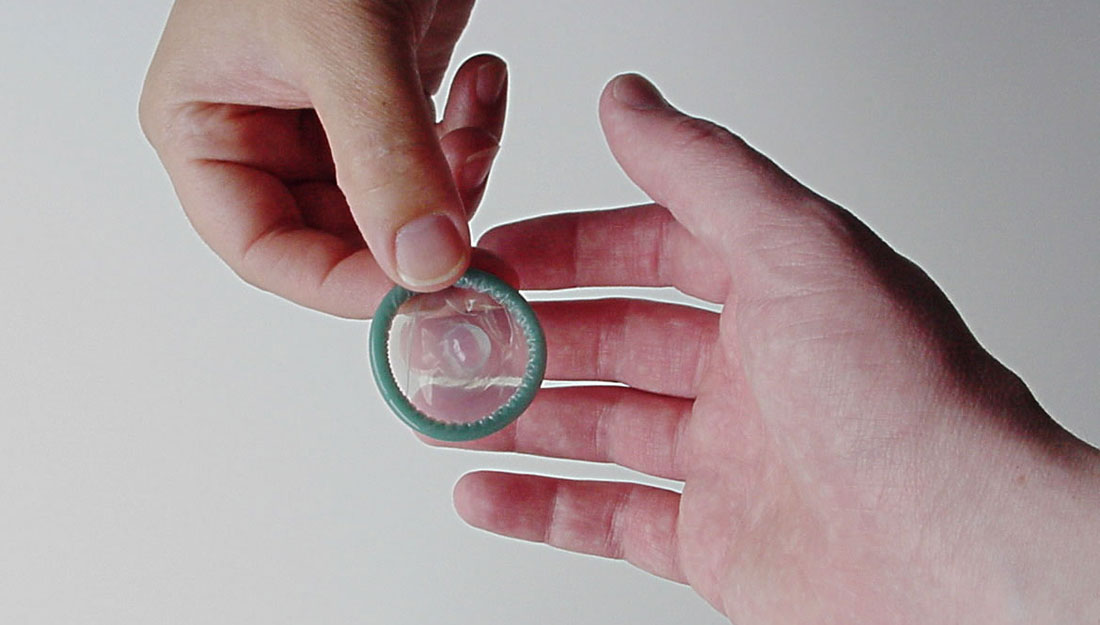 Hands handling a condom