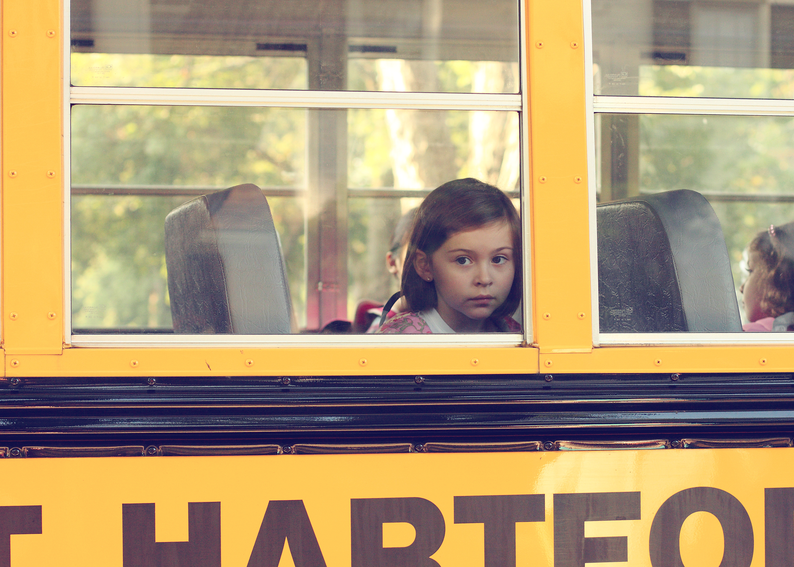 Little girl looking out of a school bus window