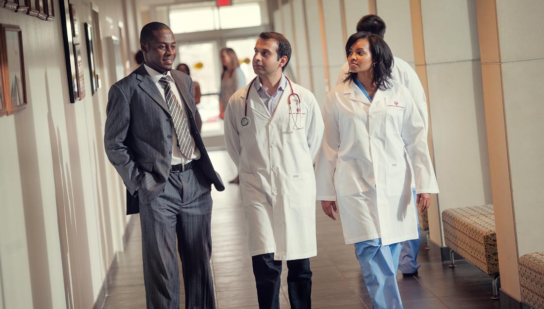 Two medical students listen to their professor.