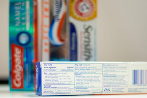 Toothpastes In The Background With A Closeup On The Ingredients List .