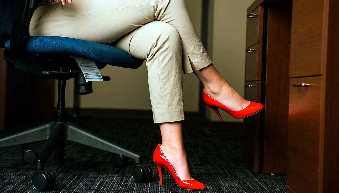 Woman at desk in bright orange high heels.