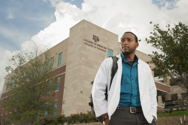 Medical Student Standing In Front Of College Of Medicine Building