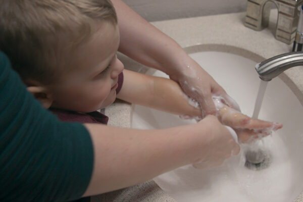 Child Getting His Hands Washed By An Adult