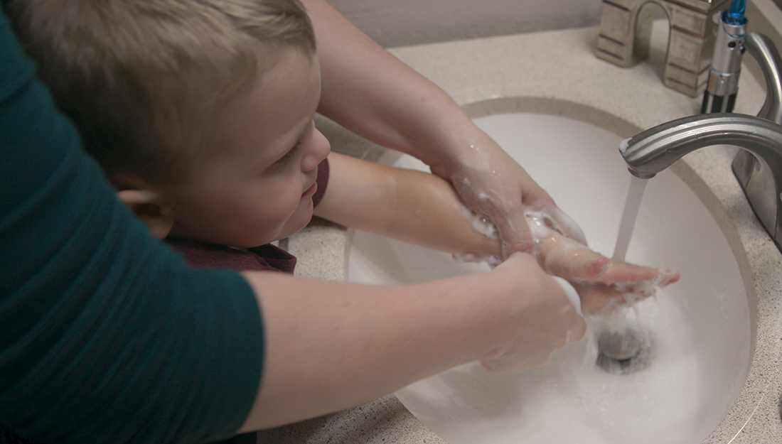 child getting his hands washed by an adult