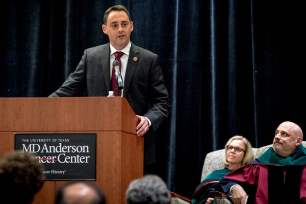 Medical Student Rhett Butler Speaks To The Crowd With Onlookers Sitting On Stage Listening