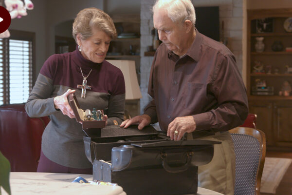 Two People Looking Through Medical Bag In Living Room.