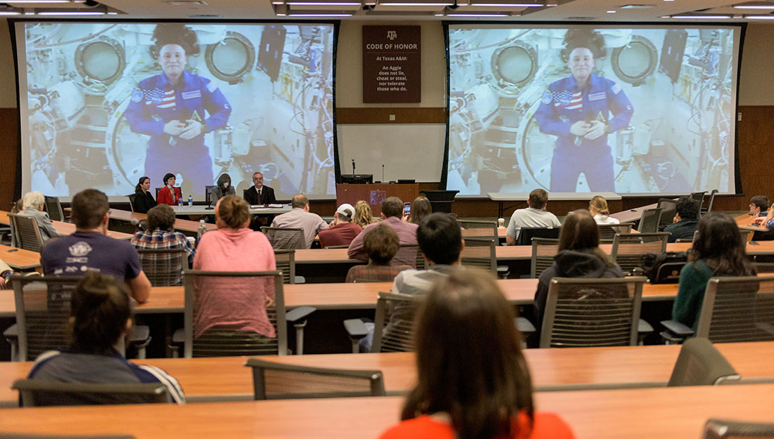 From the ISS, Chancellor speaks from a livestream to a room full of students.