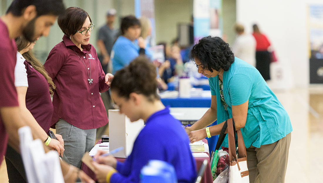 Health educators talk with participants at a community health event.