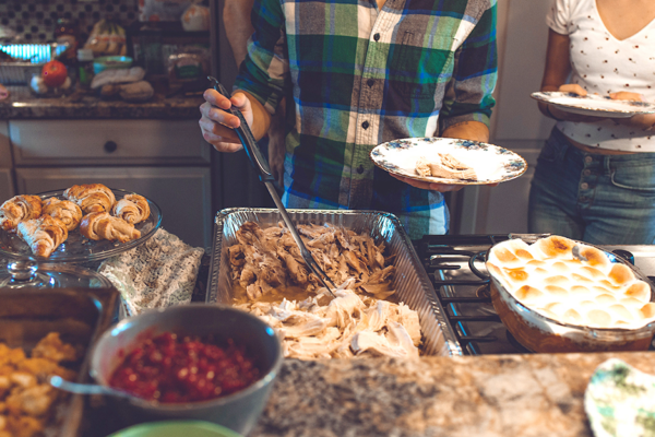 A Man Serving Himself Holiday Food Like Turkey And Baked Goods.