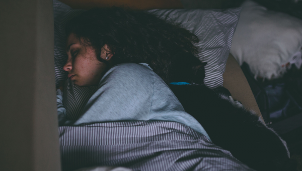 Woman asleep in a bed with a cat. Nighttime Asthma