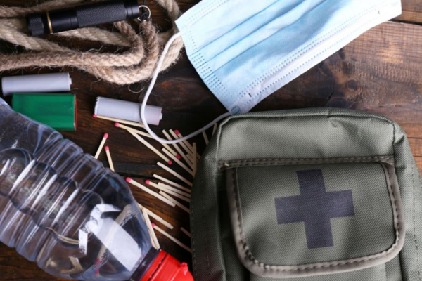 A Disaster Kit With Some Contents Like Matches, Water And Batteries Showing.