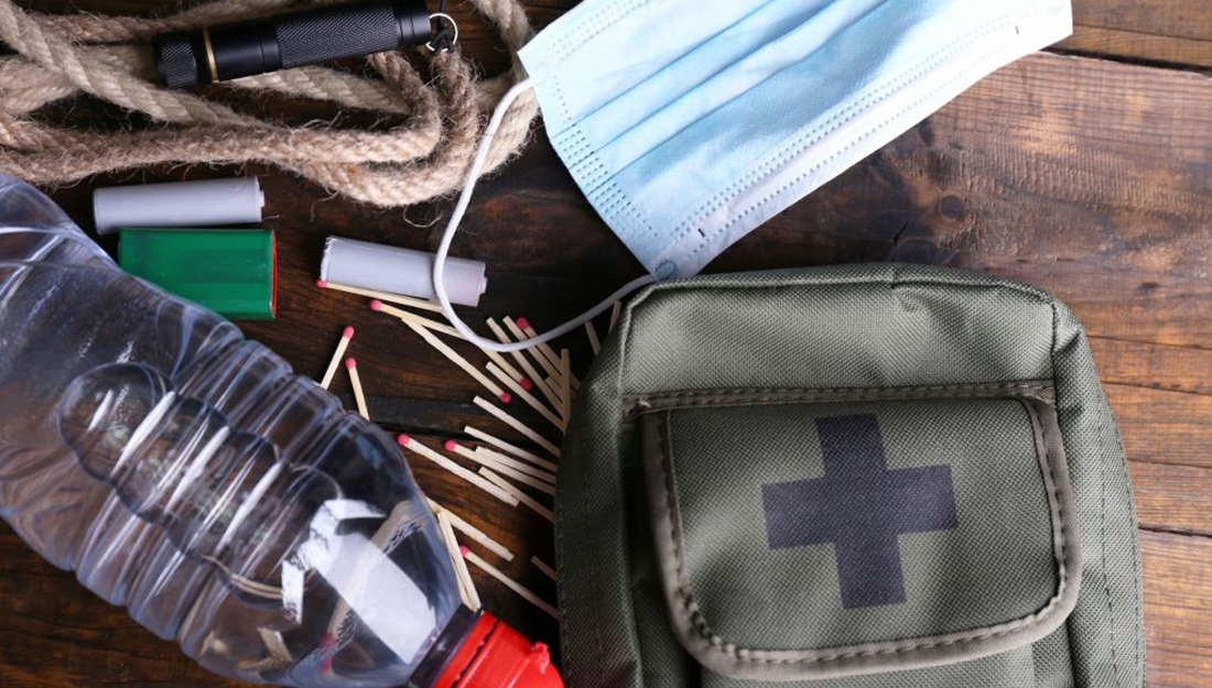 A disaster kit with some contents like matches, water and batteries showing.