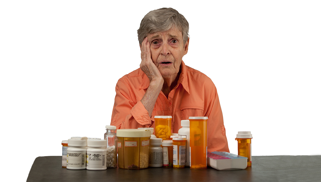 An elderly woman with medications looking overwhelmed