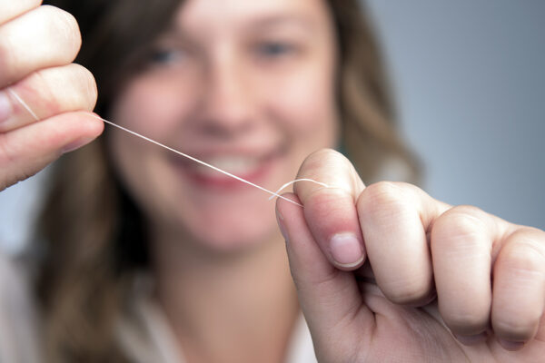 How To Properly Floss. A Young Women Holds Floss In Her Hands.