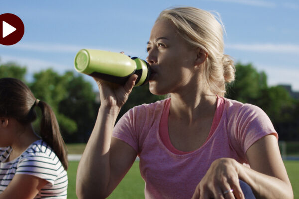 Dehydration_Hydration_a Woman Is Sitting On A Field Drinking A Water Bottle