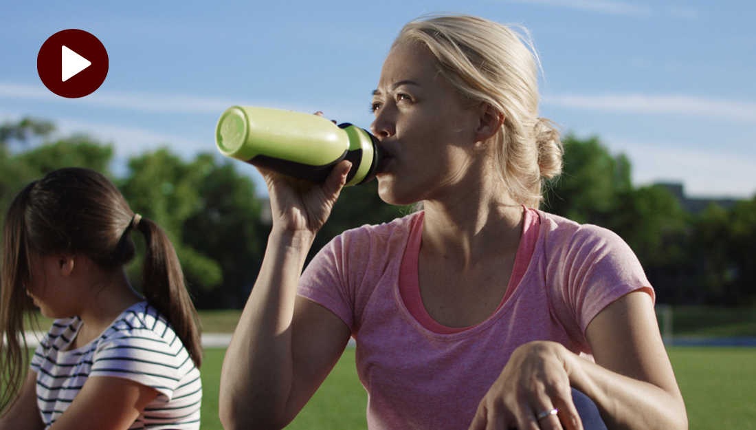 Dehydration_Hydration_a woman is sitting on a field drinking a water bottle