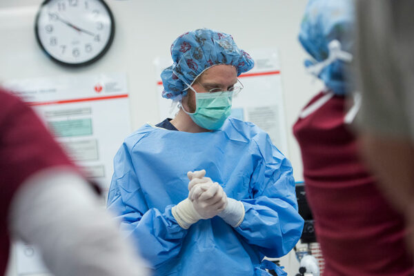 Physician In Medical Mask, Cap, Cloves And Gown