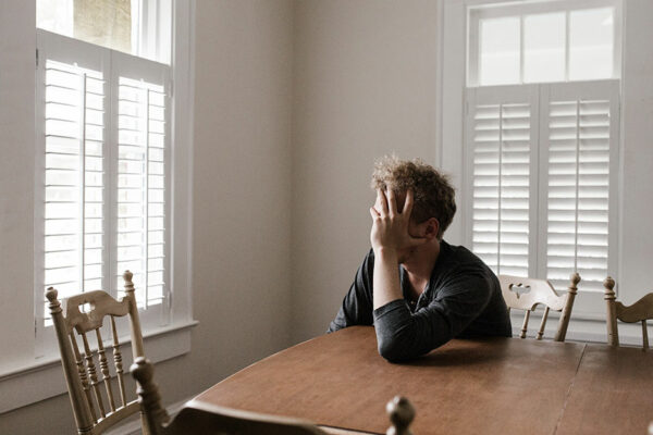 Man Resting Head In Hand Sitting At Table