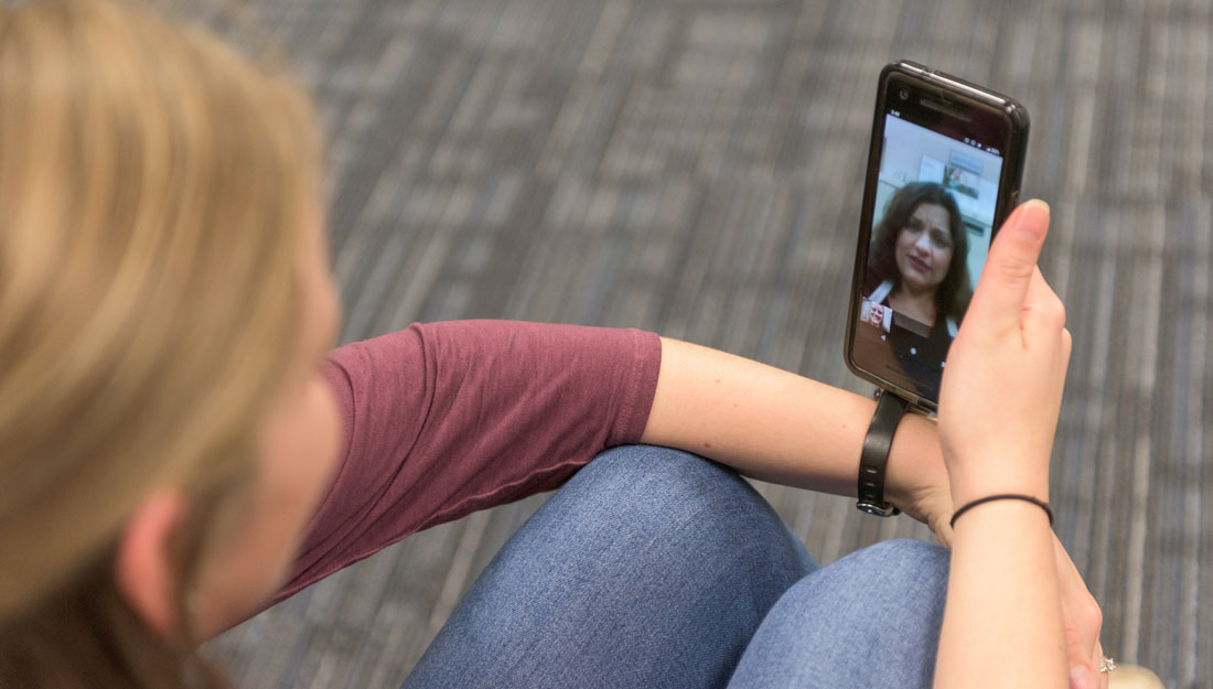 woman holding phone, talking with doctor over telemedicine