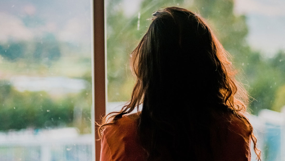 woman with dark hair looking out a window