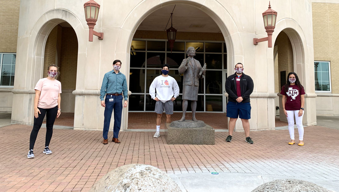 five students pose in front of Rangel College of Pharmacy building wearing hand-sewn face masks