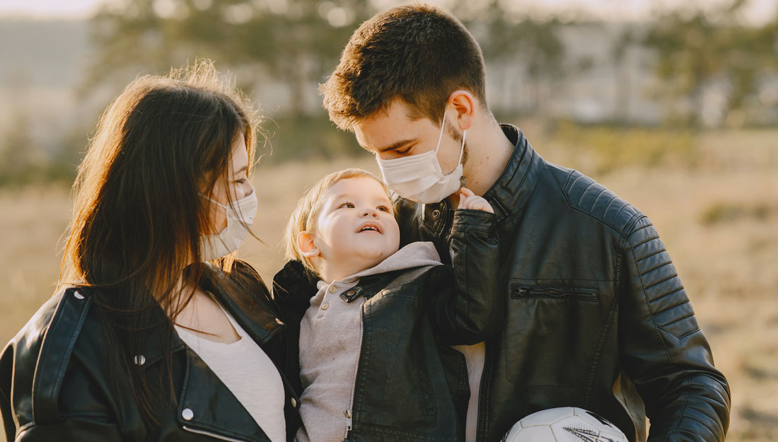 family of three wearing face coverings outdoors