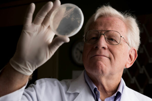 Dr. James Samuel Holds Up A Petri Dish To Take A Close Look At Pathogens