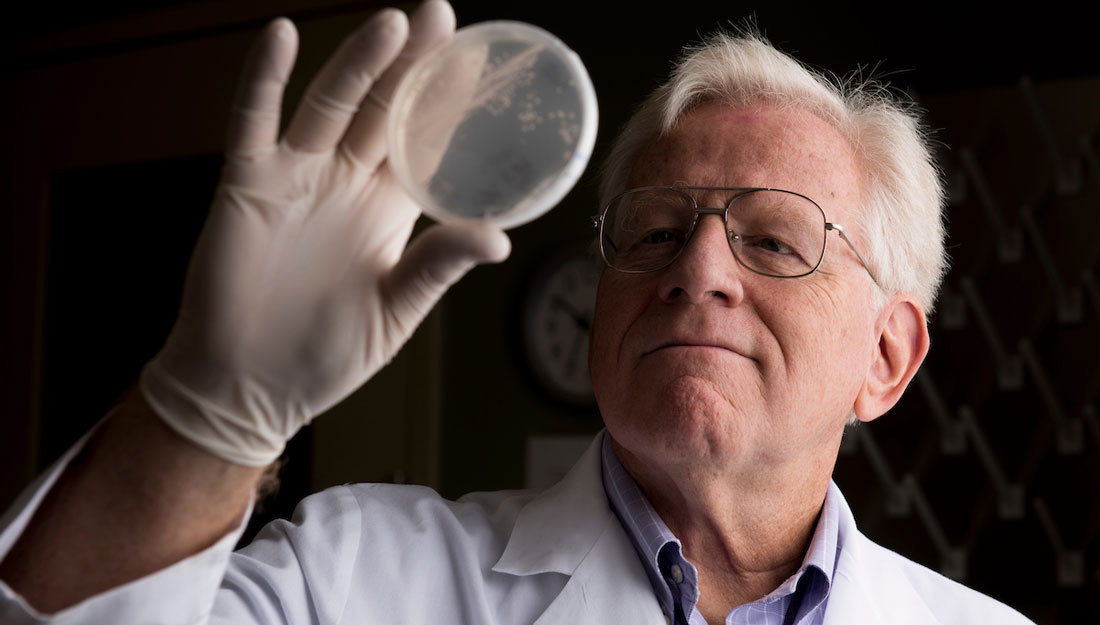 Dr. James Samuel holds up a petri dish to take a close look at pathogens