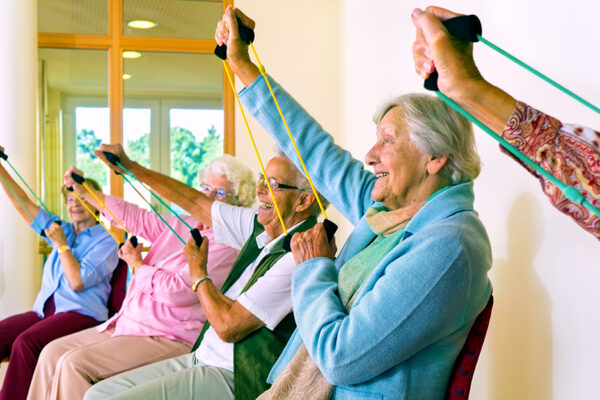 Women In Chairs Using Stretching Bands.