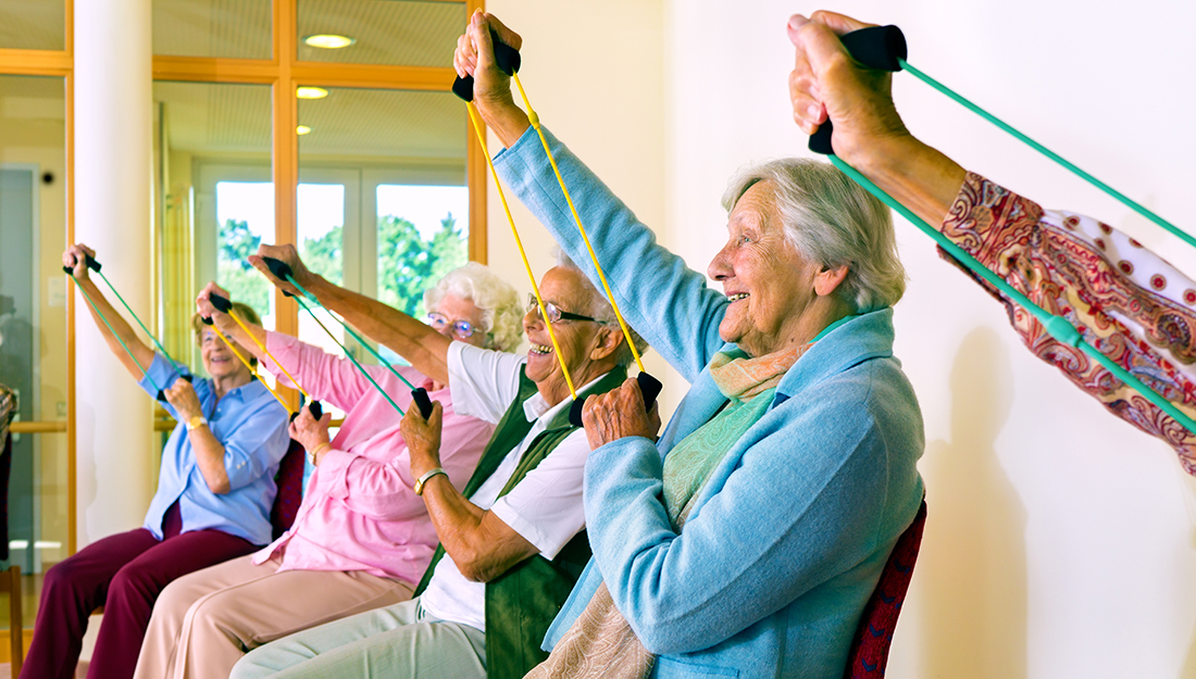 Women in chairs using stretching bands.