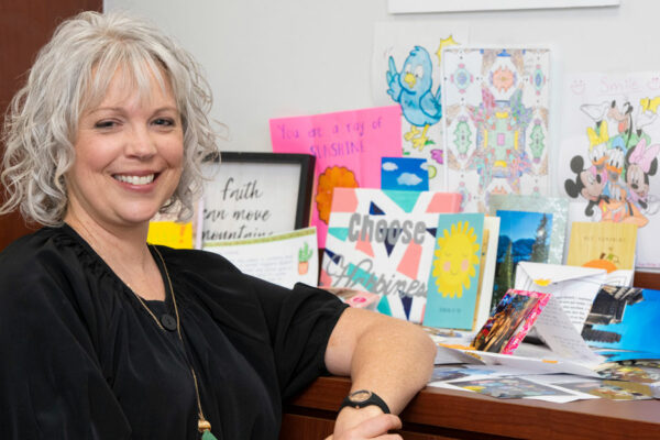 Executive Director Leigh Ann Wyatt Stands Beside Handmade Student Pen-pal Projects