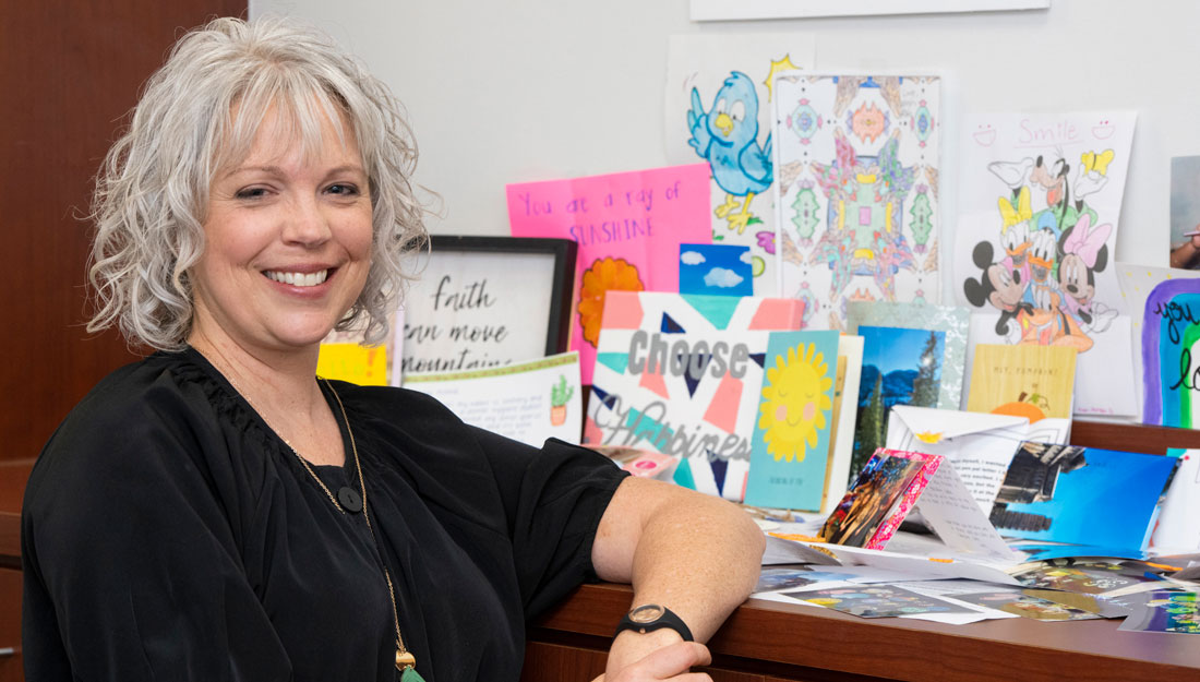 Executive Director Leigh Ann Wyatt stands beside handmade student pen-pal projects