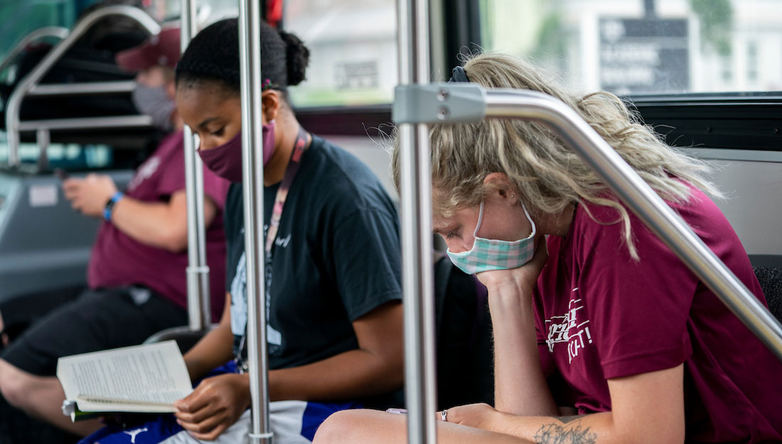 college students wearing masks ride bus