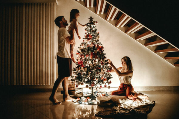 Family Of Three Decorates A Christmas Tree In Their Home