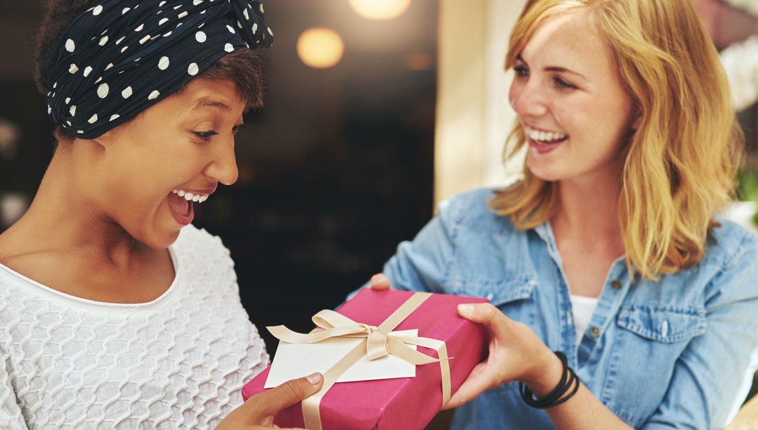 Young woman giving a friend a surprise gift