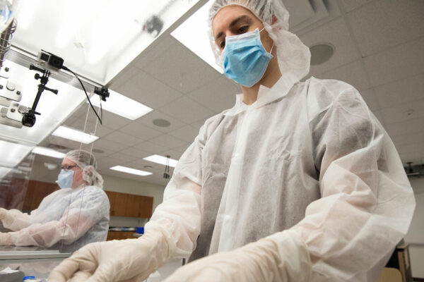 Two People Wearing Personal Protective Equipment Work In A Laboratory