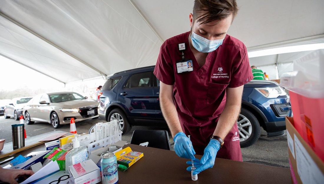 a nursing student loads a syringe with the Moderna COVID-19 vaccine at a drive-through vaccine clinic in Bryan-College Station