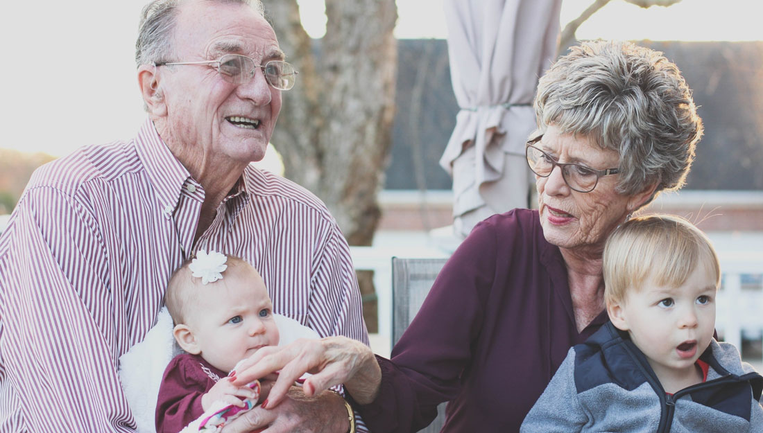 older man and woman hold a baby girl and a toddler boy