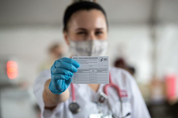 Nursing Student Holds Up A Vaccination Record Card