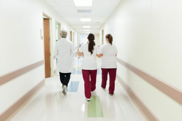 Nurses Walk In Hallway, Away From Viewer