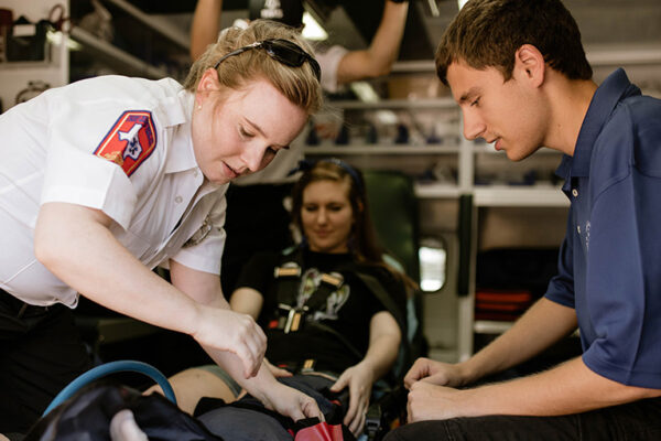 Two Emergency Medical Responders Work Together On A Patient In The Back Of An Ambulance