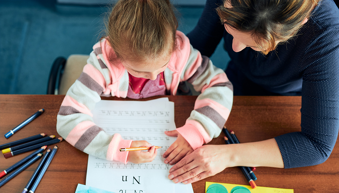 Preschool child doin homework with an adult.