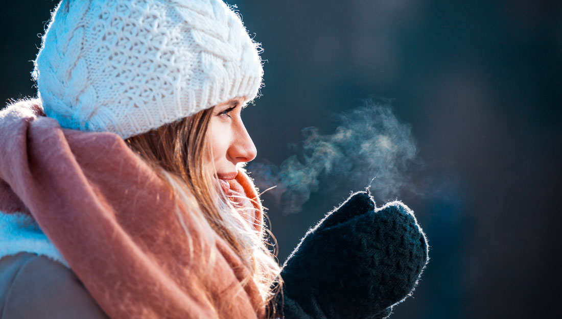 woman rubs mittened hands together in cold air