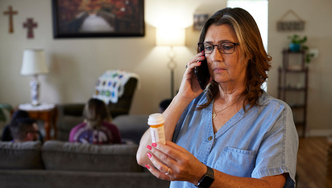 woman looks at prescription bottle will holding phone