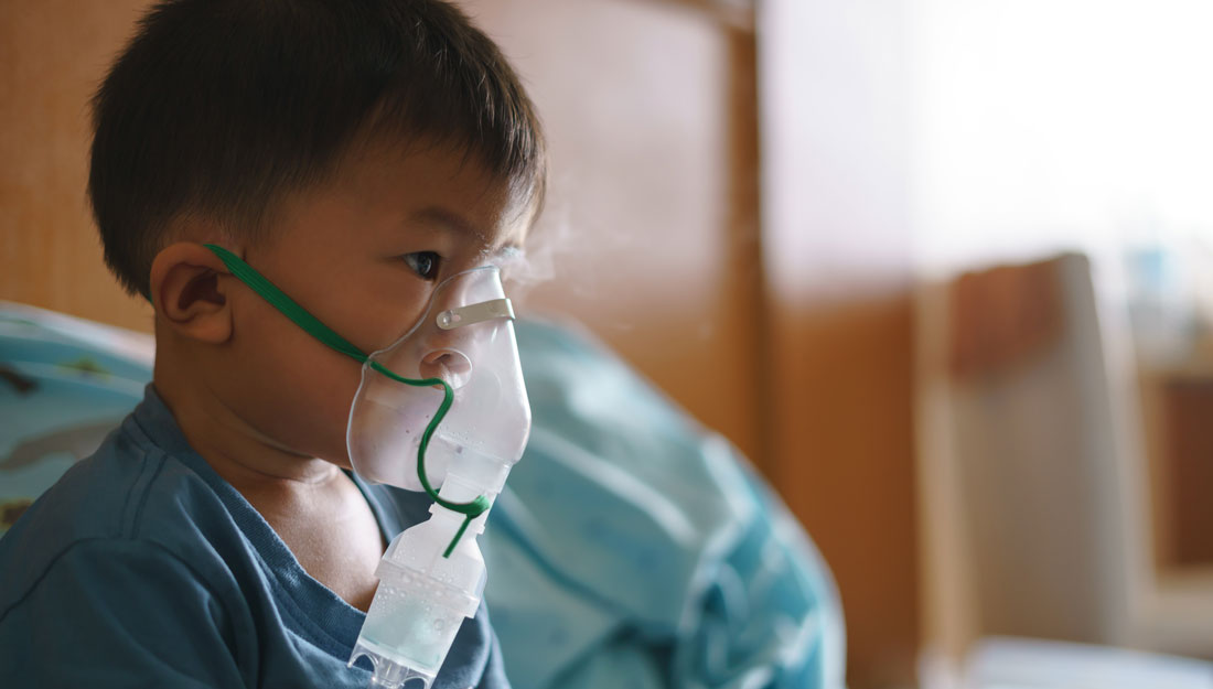 boy sittin gin hospital bed uses nebulizer