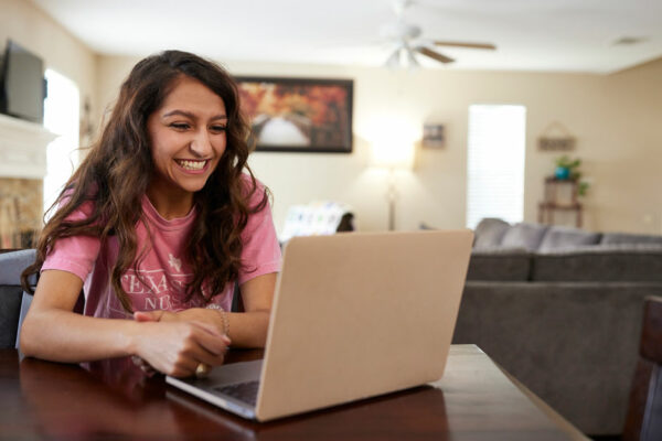 College Student Interacts Over Videoconferencing On Laptop In Home Environment