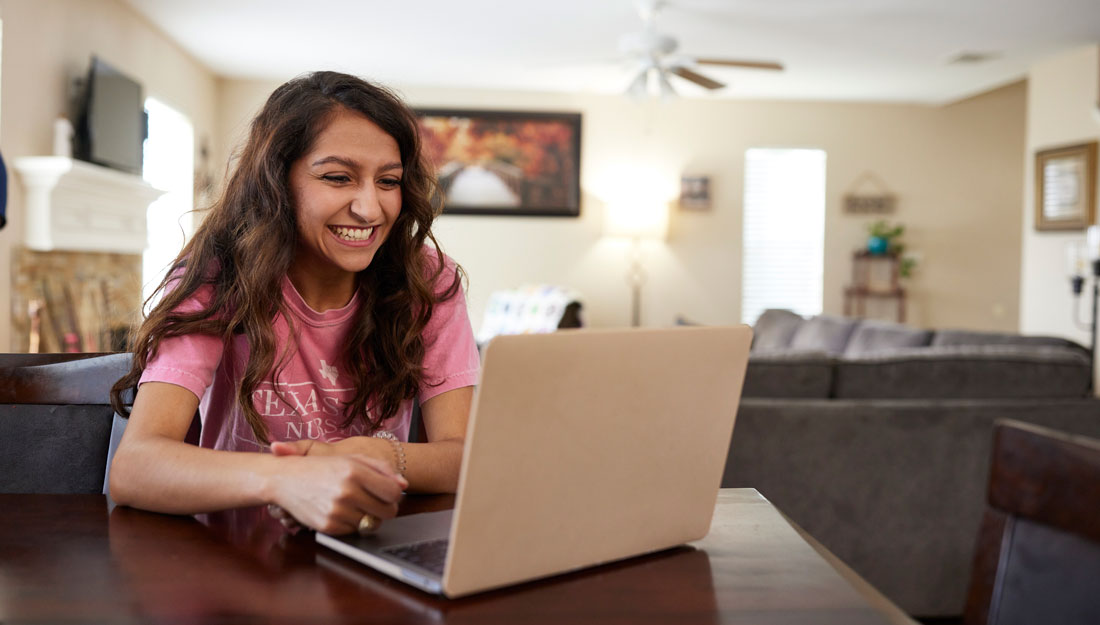 college student interacts over videoconferencing on laptop in home environment