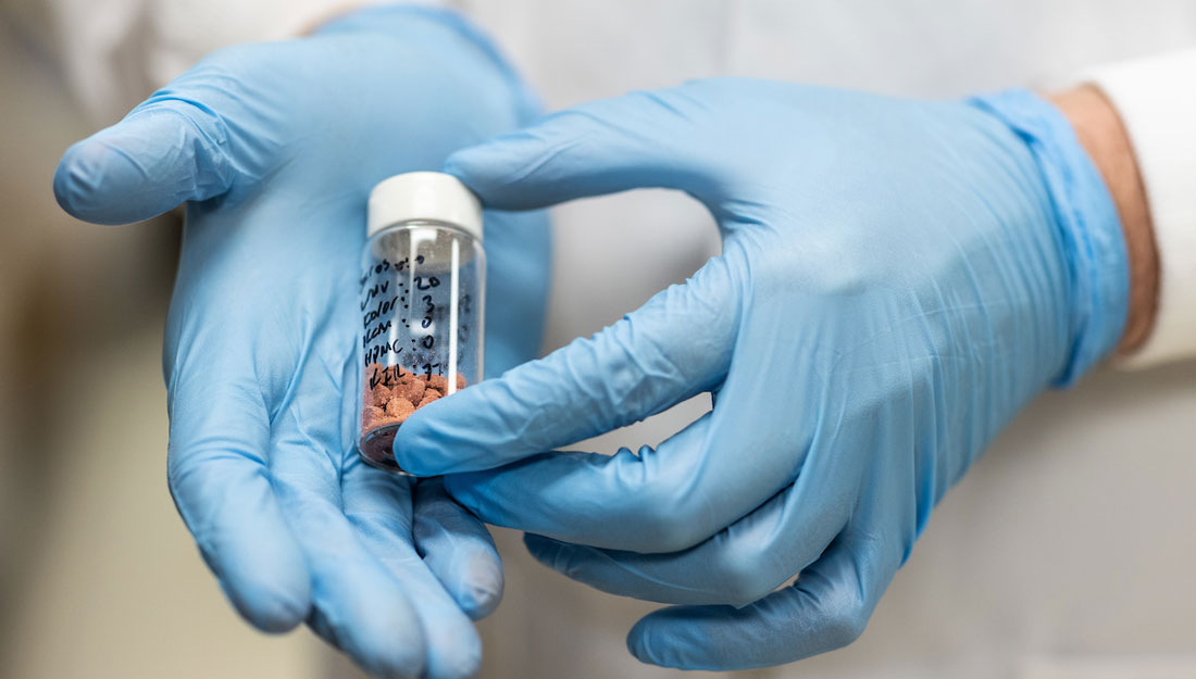 lab worker holds a vial filled with 3D printed pills