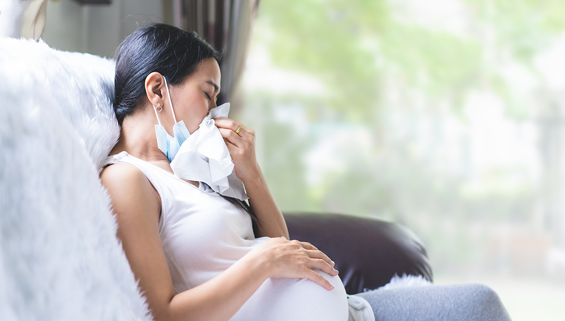 Pregnant woman blows her nose into a tissue